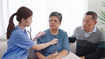 Asian female nurse caregiver using stethoscope checking heartbeat and lungs of mature middle aged...