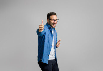 Portrait of satisfied cheerful handsome businessman showing thumbs up isolated on gray background