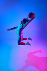 Full-length image of young professional basketball player in motion, training, playing over...