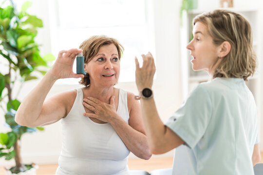 Elderly woman using asthma inhaler in clinic