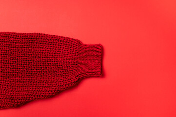 Red knitted sweater on red background top view with copy space. Texture of woolen cotton winter autumn cozy sweater, clothes. Knitted jumper, pullover, fashion. Sweater close-up