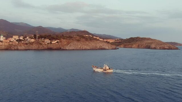 Le chalutier s'approche du port le long de la cote vermeille. The trawler approaches the  harbour