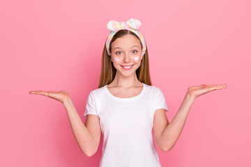 Portrait of charming happy girl arms palms demonstrate empty space vs scales ad isolated on pink...