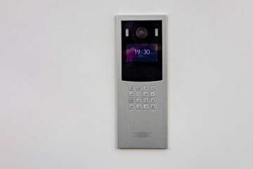Doorbell with video camera and microphone, on the white wall of an apartment building, doorbell camera.