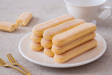 Lady finger biscuits, Italian dessert and sponge cookie on white plate and coffee cup.