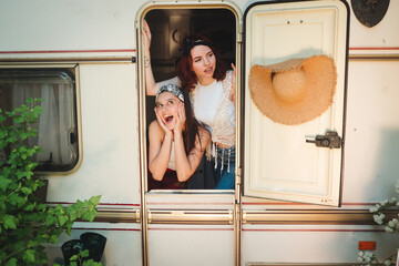 Happy hippie friends are having a good time together in a camper trailer. Holiday, vacation, trip concept.