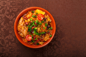 hot cholent sprinkled with green onions in a clay plate on the table