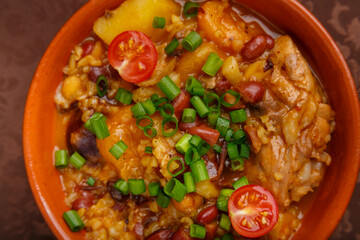 ready-made cholent dish, sprinkled with green onions, in a clay