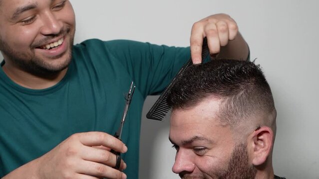 Client with satisfactory user experience - Barber cutting client with scissors while hair remains fall - Trusted stylist - Barber at home