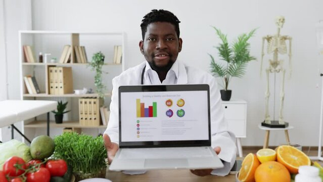 Portrait of skilled nutrition specialist sitting at desk with remote device and looking at camera in modern medical clinic. Qualified man explaining growth of cases with gastritis and stomach ulcers.