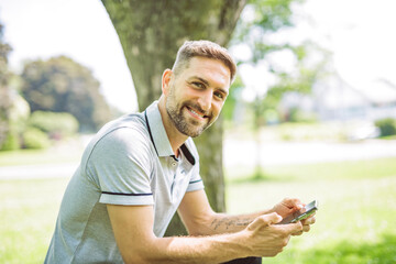 Happy cheerful man with a cellphone outdoors in nature, freedom and happiness concept