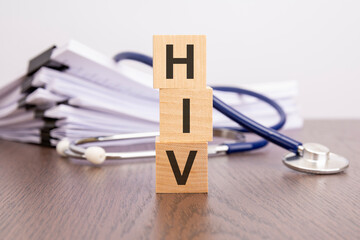 text HIV written on wooden cubes near a stethoscope on a paper background. HIV - human immunodeficiency virus, medical concept