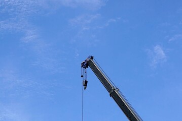 A crane lifting heavy load on blue sky background, closeup of photo.