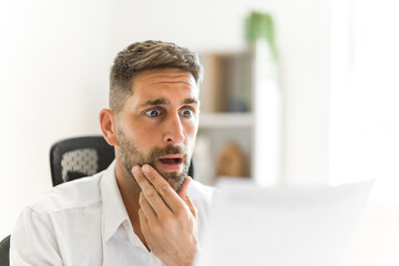 Worried business man middle-aged man reading unexpected paper document.