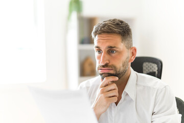 Worried business man middle-aged man reading unexpected paper document.