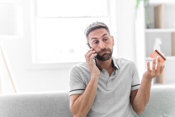Worried middle-aged man holding credit card and talk to a help person