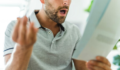 Worried middle-aged man reading unexpected paper document.