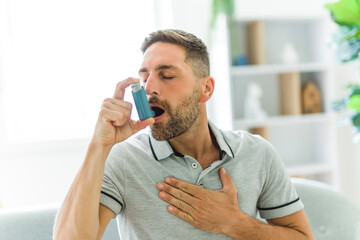 man using asthma inhaler at home