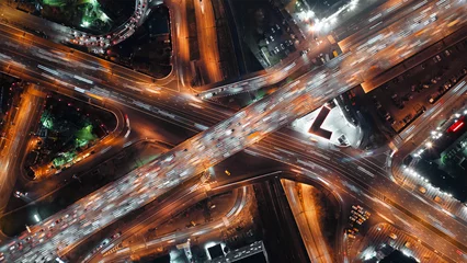 Photo sur Plexiglas Autoroute dans la nuit Top-down view of fast-moving cars on a highway, intense traffic during rush hour at a city crossroad, modern multi-level intersection with beautifully moving vehicles.