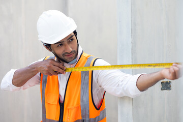 professional engineer indian man using measure tape and working at precast concrete wall factory....