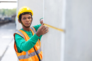 Senior asian man worker using measure tape and working at precast concrete wall factory. Yellow...