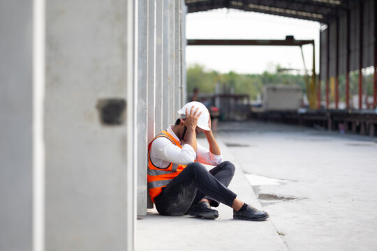 Unhappy lonely depressed and sad feeling. Asian Engineer man working at precast factory. Engineering worker in safety hardhat at factory industrial facilities