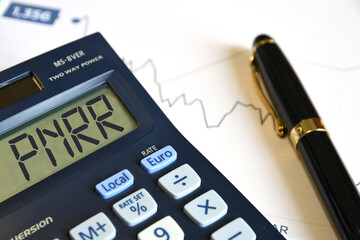 Calculator with 'PNRR' sign along with financial charts and a pen.