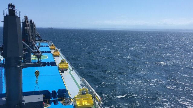 View from the bridge of the handymax bulk carrier to the holds and the ocean during the day. Large cargo ship in the ocean