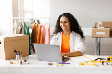 Fashion Designer Arabic Lady Websurfing On Laptop Working In Showroom