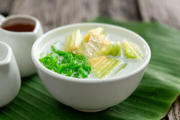 Close up of Lod Chong Thai dessert topped with coconut milk and pandan leaf followed by green...