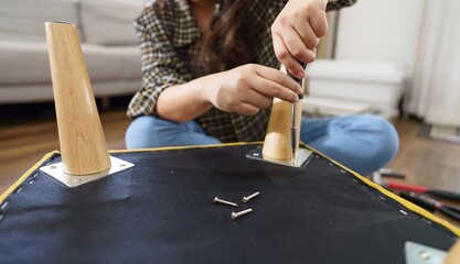 Asian Woman self repairs furniture renovation using equipment to diy repairing furniture sitting on the floor at home