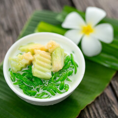 Appetizing lod chong placed on a green banana leaf decorated with white champa flowers on a wooden table.