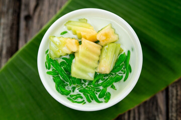 Top view of Lod Chong is a dessert made from rice flour. green from pandan leaves and fresh coconut milk laid on a wooden background.