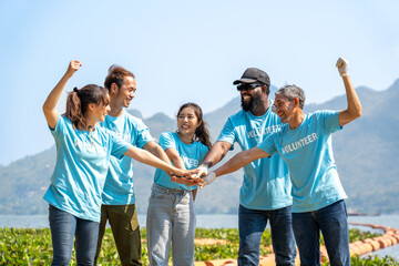Group of happy diverse multi-ethnic volunteers joining hands stack together and raising hands with smile to show the power of unity in charity work, key to success in making future a better world