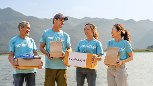 group of diverse volunteer carrying donation box raising money charitable working together for campaign sharing to help underprivileged people by donate food, clothing, support education environment - Powered by Adobe