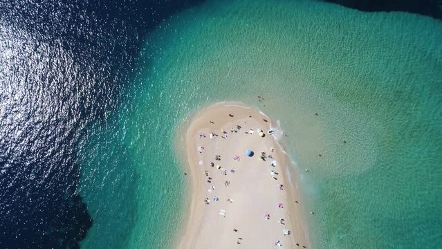 Drone view of Zlatni Rat (Golden Horn or Golden Cape), famous beach on Brac Island in Croatia, with people swimming. Tourists enjoying summer travel in Europe. Croatian attraction on Mediterranean Sea
