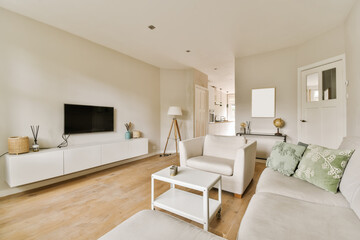 a living room with wood flooring and white couches in front of a flat screen tv on the wall
