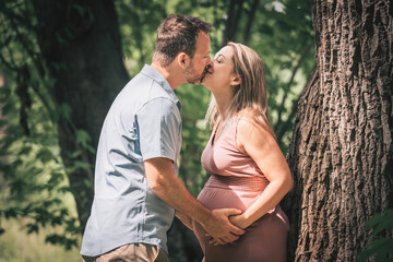 Fototapeta premium Family together in the summer park. Woman is pregnant