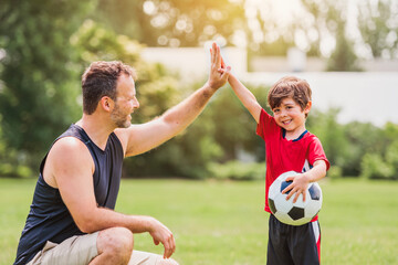 Young soccer player having fun on a field with his father