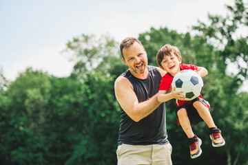 Young soccer player having fun on a field with his father
