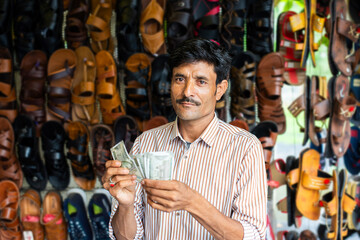 Indian man selling footwear or chappal at roadside shop