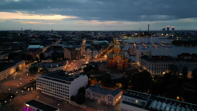 Upenski Cathedral amid lit buildings and streets in Helsinki Harbor at dawn