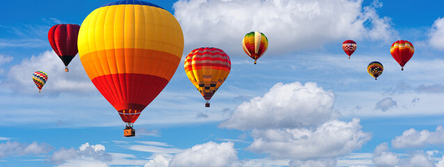 Obraz premium Hot Air Balloon Ride in blue sky white clouds background for wide banner of travel agency or adventure tour. Romance of ballooning in a good weather. Hot air balloons flies in blue sky. Copy space