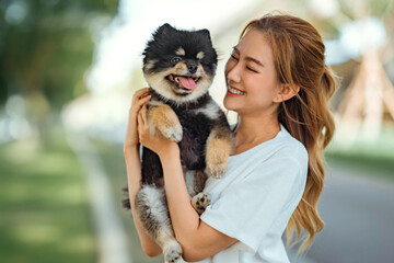 Obraz premium Happy asian woman playing with dog together in park outdoors, summer vacation.