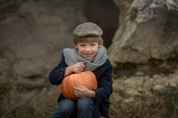 boy blindin without front teeth in vintage clothes is sitting with a pumpkin
