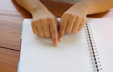 Visually impaired person reads with his fingers a book written in braille It is written for those...
