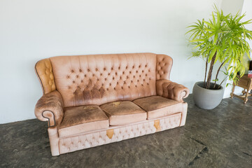 Empty old brown leather sofa seat on cement floor,black classic loft interior in living room,cafe or restaurant interior design concept.