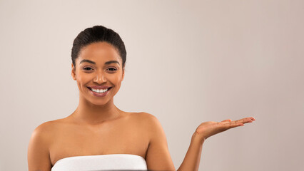 Positive attractive young black lady showing something on hand