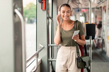 Woman In Tram Holding Phone Listening Music In Earphones Inside