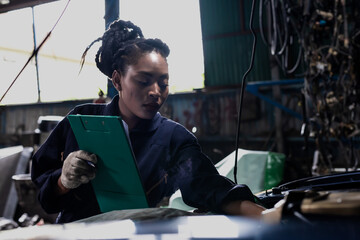Black Car Mechanic woman holding clipboard working in auto repair garage